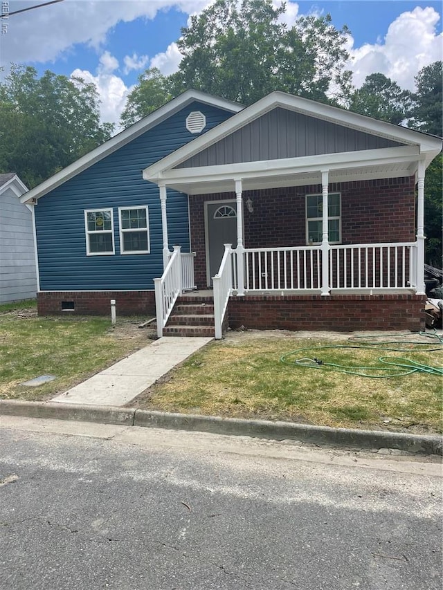 712 Norfleet St, Franklin, VA 23851 - view of front of home with covered porch, a front yard, and brick siding