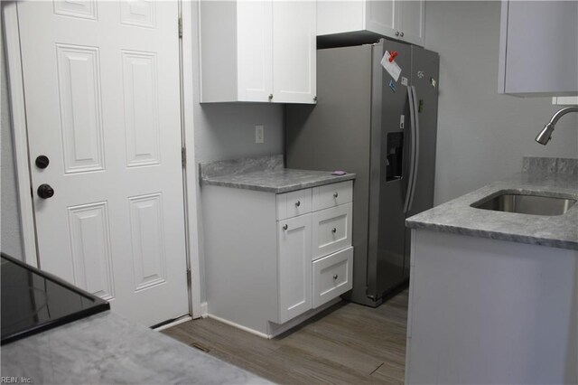 1307 Hibie St, Norfolk, VA 23523 - kitchen with a sink, wood finished floors, white cabinetry, stainless steel refrigerator with ice dispenser, and light stone countertops