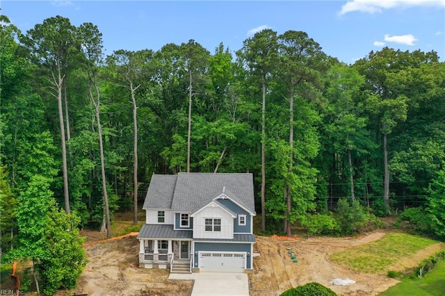 107 Wheeley Cir, Yorktown, VA 23693 - view of front facade with concrete driveway, metal roof, a garage, a standing seam roof, and a forest view