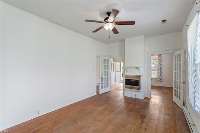 unfurnished living room with french doors, heating unit, hardwood / wood-style floors, and a baseboard heating unit