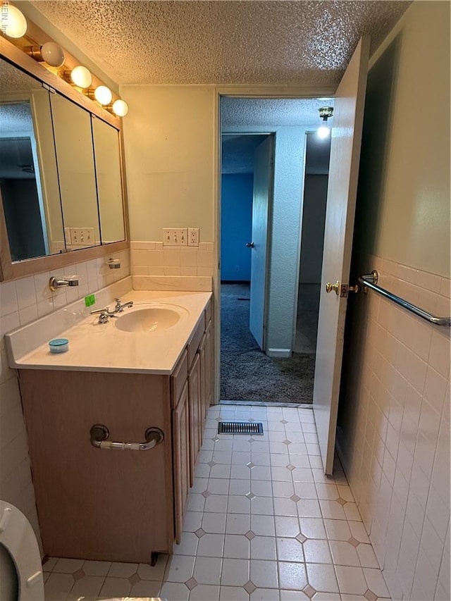 1224 Old Clubhouse Rd, Virginia Beach, VA 23453 - bathroom featuring a textured ceiling, tile walls, vanity, and a wainscoted wall