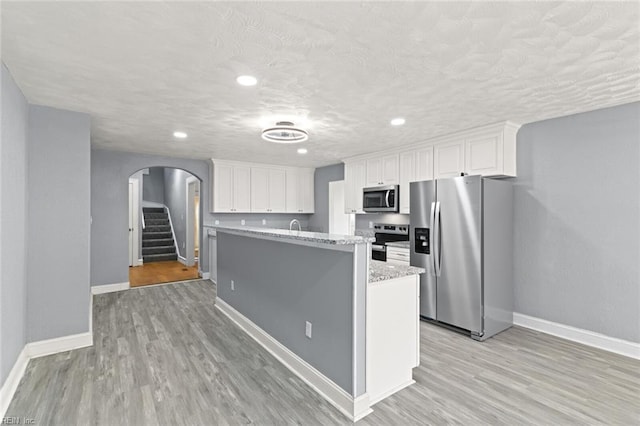 1250 27th St, Newport News, VA 23607 - kitchen featuring stainless steel appliances, arched walkways, baseboards, light wood-style flooring, and white cabinets