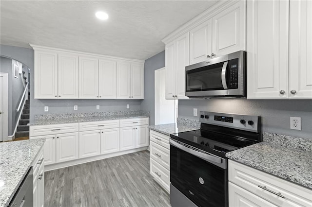 1250 27th St, Newport News, VA 23607 - kitchen featuring stainless steel appliances, arched walkways, white cabinetry, light wood-style flooring, and a textured ceiling