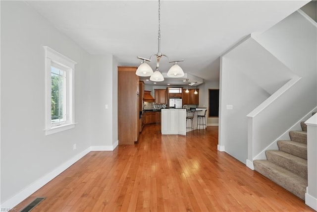 9628 7th Bay St Unit A, Norfolk, VA 23518 - unfurnished living room featuring a chandelier, baseboards, light wood-type flooring, and stairs