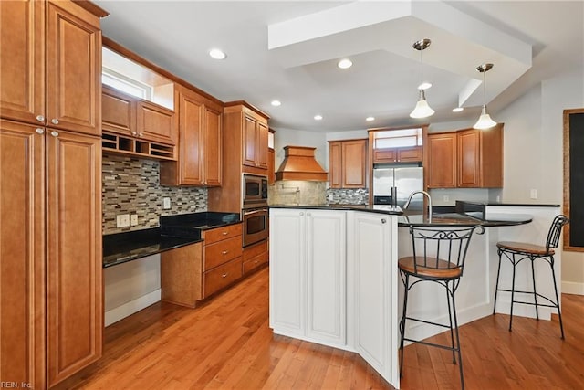 9628 7th Bay St Unit A, Norfolk, VA 23518 - kitchen with appliances with stainless steel finishes, dark countertops, brown cabinetry, light wood finished floors, and a kitchen breakfast bar