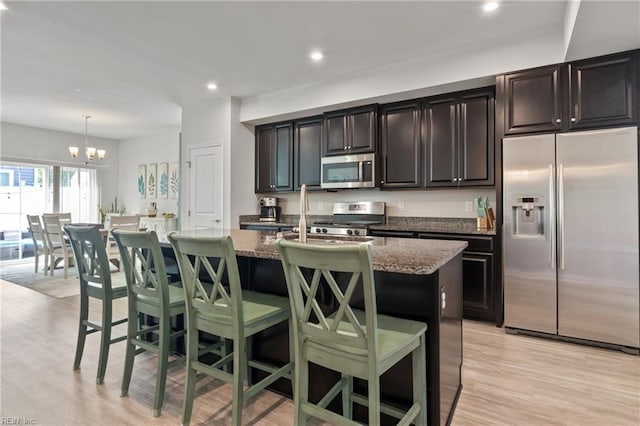 705 Mapleleaf Ln, Virginia Beach, VA 23462 - kitchen featuring appliances with stainless steel finishes, a kitchen island with sink, a chandelier, dark stone counters, and a breakfast bar area