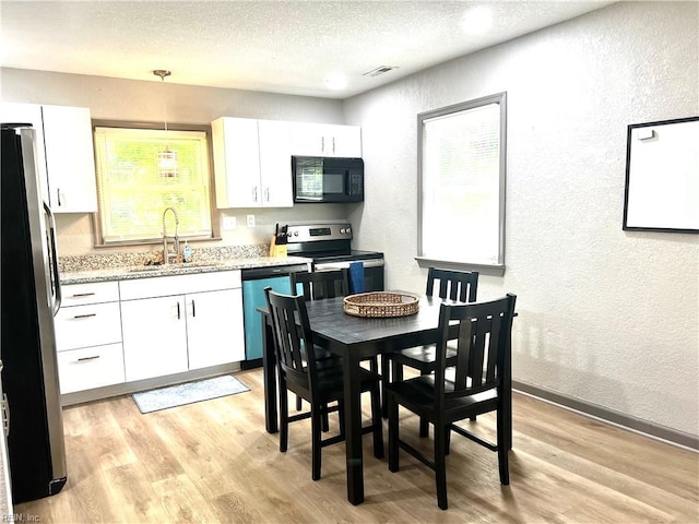 1628 Bourbon Ave, Norfolk, VA 23509 - kitchen with a sink, stainless steel appliances, a textured wall, white cabinets, and light wood-style floors