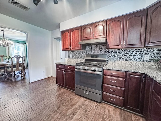 1907 Eastborne Dr, Virginia Beach, VA 23454 - kitchen with stainless steel gas range oven, under cabinet range hood, wood finished floors, light stone counters, and decorative backsplash