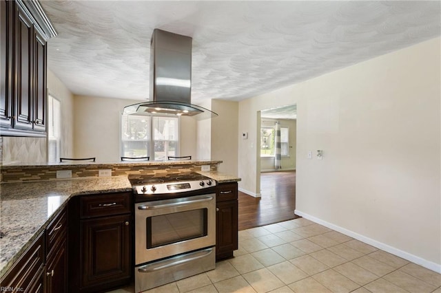 2212 Wildwood Rd, Chesapeake, VA 23323 - kitchen with island exhaust hood, stainless steel gas stove, plenty of natural light, light tile patterned floors, and a textured ceiling