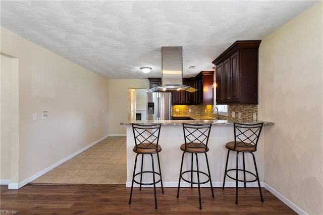 2212 Wildwood Rd, Chesapeake, VA 23323 - kitchen with island range hood, stainless steel fridge with ice dispenser, a peninsula, light stone countertops, and a breakfast bar area