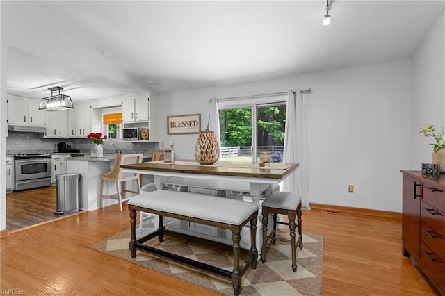 dining area featuring light wood-style flooring and baseboards