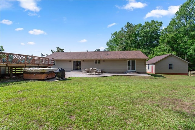 back of house featuring a hot tub, a patio, and a lawn