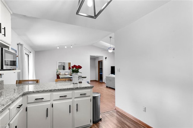 kitchen featuring stainless steel microwave, wood finished floors, open floor plan, a peninsula, and ceiling fan