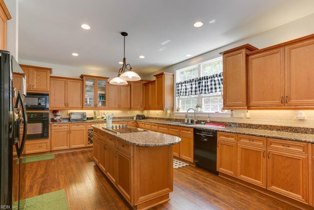 kitchen featuring black appliances, a sink, backsplash, dark stone countertops, and recessed lighting