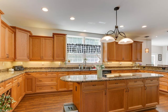 kitchen featuring a sink, dark wood-style flooring, a center island, stone countertops, and recessed lighting