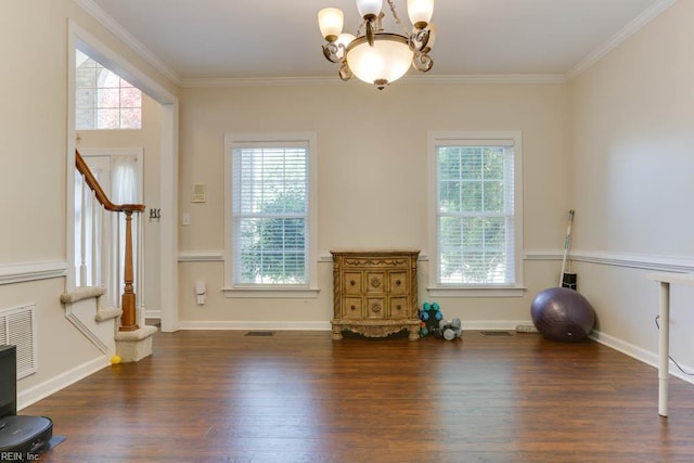 exercise area with a chandelier, crown molding, wood finished floors, and baseboards