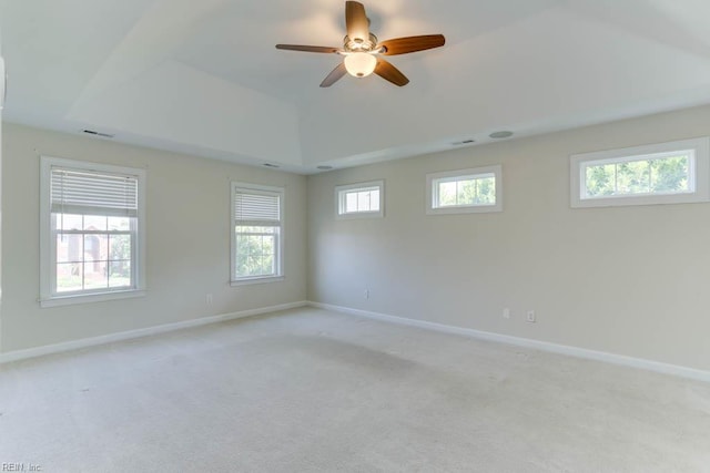 empty room featuring light carpet, baseboards, a tray ceiling, and a ceiling fan
