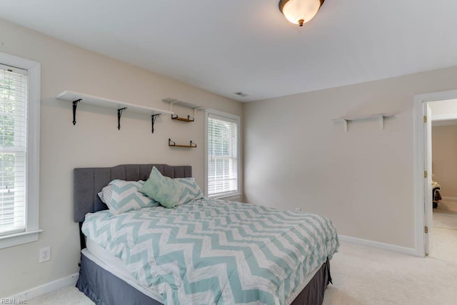 bedroom featuring multiple windows, light carpet, and baseboards