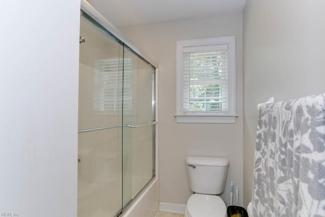 bathroom with toilet, baseboards, and enclosed tub / shower combo