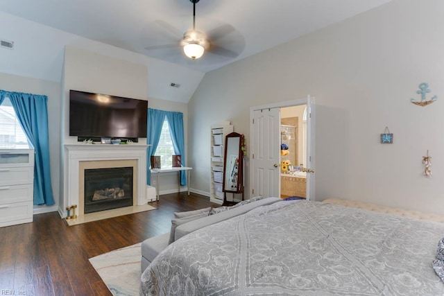 bedroom featuring vaulted ceiling, wood finished floors, a fireplace with flush hearth, baseboards, and ceiling fan