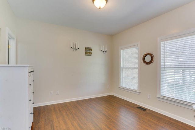 empty room with dark wood finished floors and baseboards