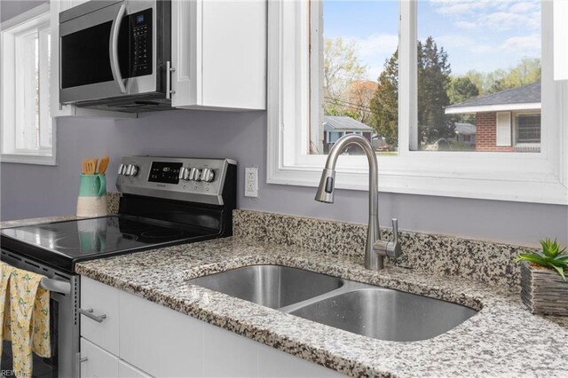 910 Truman Rd, Suffolk, VA 23434 - kitchen featuring appliances with stainless steel finishes, a sink, white cabinets, and light stone countertops