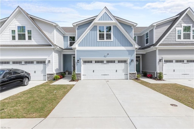view of front of property with board and batten siding, driveway, stone siding, a garage, and a front lawn