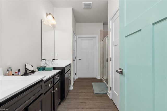 bathroom featuring a shower stall, wood finished floors, and vanity