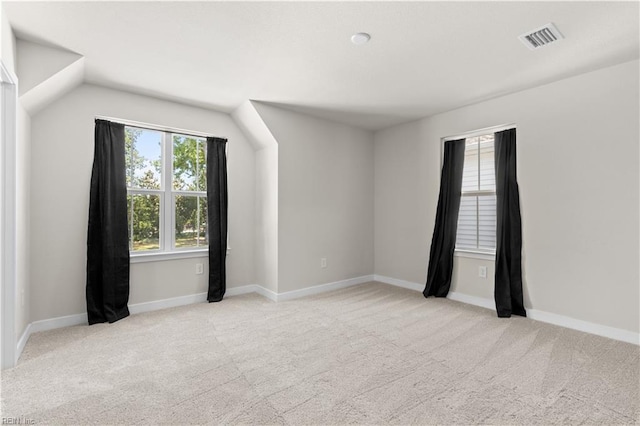 unfurnished room featuring light carpet, lofted ceiling, and baseboards
