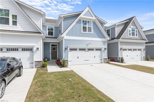 craftsman inspired home featuring board and batten siding, stone siding, driveway, a front yard, and a garage