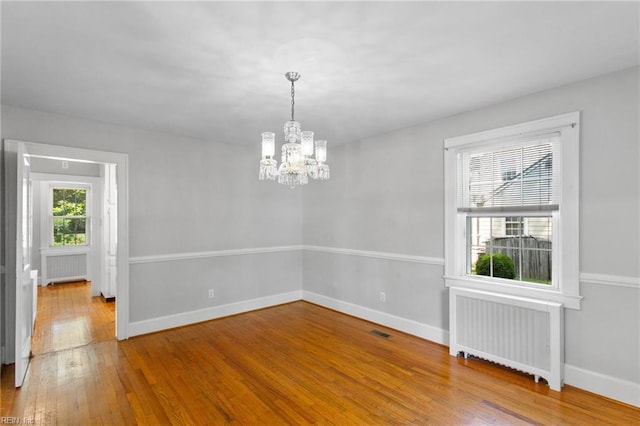 9913 River Rd, Newport News, VA 23601 - spare room featuring radiator heating unit, a chandelier, hardwood / wood-style flooring, and baseboards