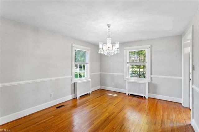 9913 River Rd, Newport News, VA 23601 - empty room featuring radiator, a chandelier, wood-type flooring, and plenty of natural light