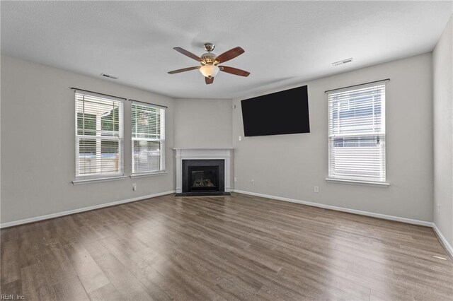 3001 Ravine Gap Dr, Suffolk, VA 23434 - unfurnished living room featuring ceiling fan, wood finished floors, a fireplace with flush hearth, and baseboards