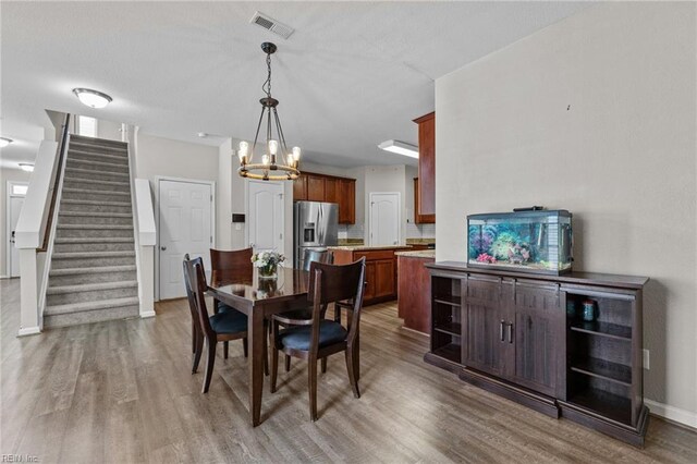 3001 Ravine Gap Dr, Suffolk, VA 23434 - dining space with wood finished floors, a chandelier, stairway, and baseboards