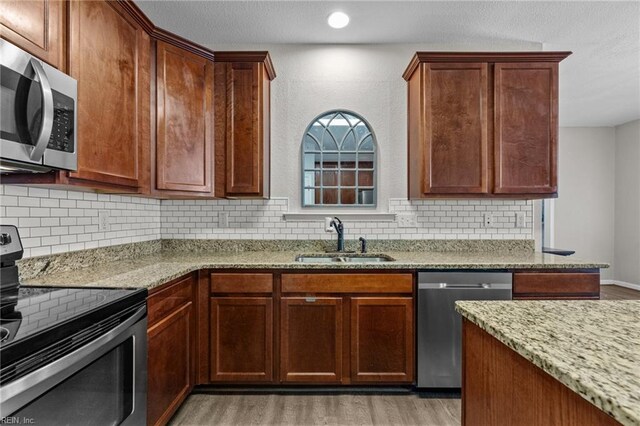 3001 Ravine Gap Dr, Suffolk, VA 23434 - kitchen with appliances with stainless steel finishes, a sink, light stone countertops, light wood-style flooring, and decorative backsplash