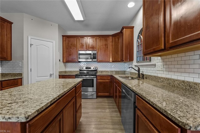 3001 Ravine Gap Dr, Suffolk, VA 23434 - kitchen featuring appliances with stainless steel finishes, a sink, wood finished floors, light stone counters, and decorative backsplash
