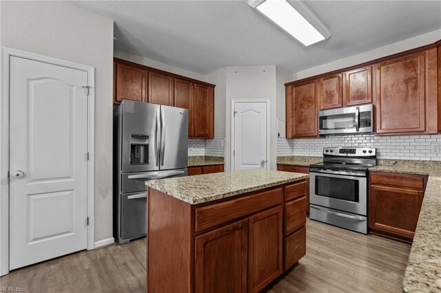 3001 Ravine Gap Dr, Suffolk, VA 23434 - kitchen featuring stainless steel appliances, light wood-style flooring, backsplash, and light stone counters
