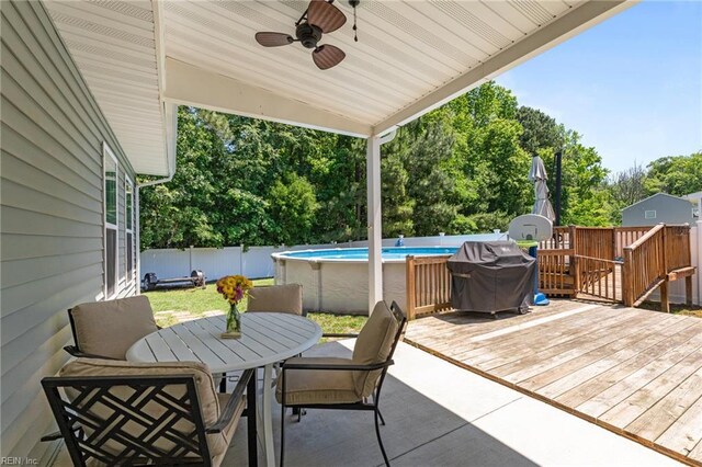 3001 Ravine Gap Dr, Suffolk, VA 23434 - wooden terrace with outdoor dining space, a grill, a fenced backyard, a ceiling fan, and view of wooded area
