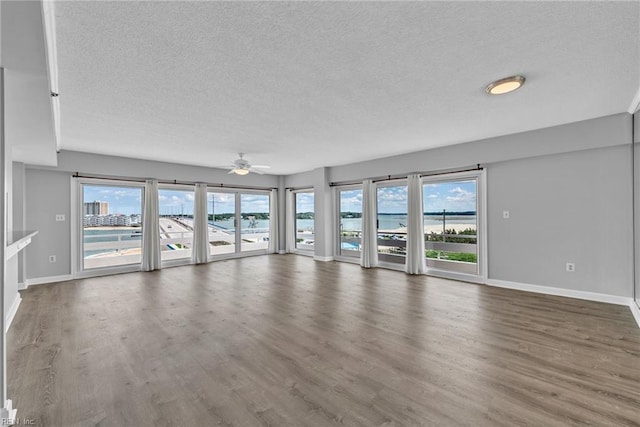 3556 Shore Dr Unit 704, Virginia Beach, VA 23455 - unfurnished living room with a textured ceiling, healthy amount of natural light, baseboards, a ceiling fan, and wood finished floors