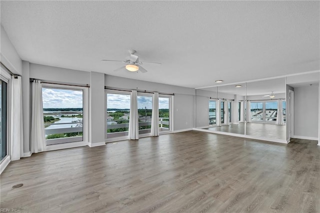 3556 Shore Dr Unit 704, Virginia Beach, VA 23455 - unfurnished living room with a ceiling fan, baseboards, healthy amount of natural light, wood finished floors, and a textured ceiling