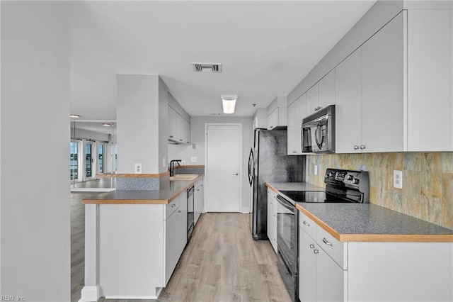 3556 Shore Dr Unit 704, Virginia Beach, VA 23455 - kitchen featuring black appliances, a sink, decorative backsplash, light wood-style flooring, and a peninsula