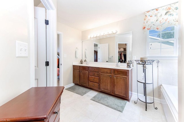 full bathroom with double vanity, a spacious closet, a tub, tile patterned flooring, and baseboards