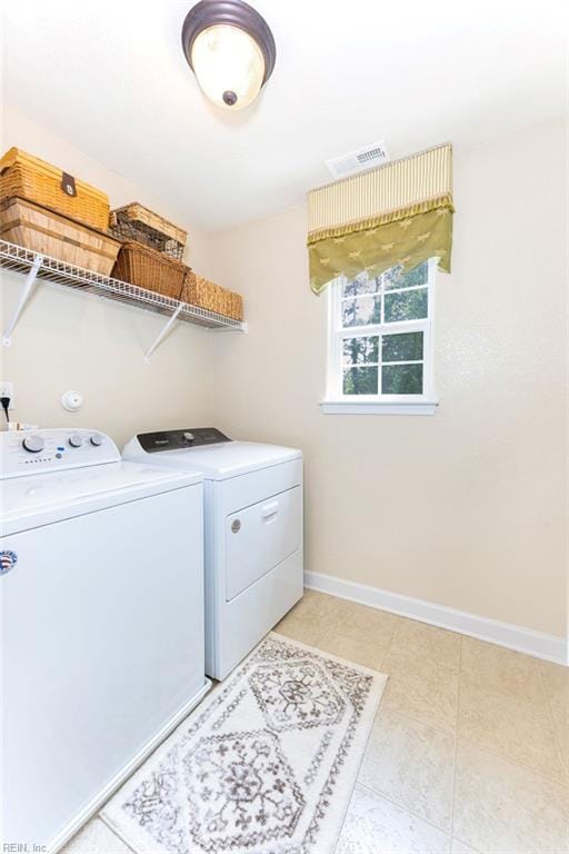 laundry area featuring separate washer and dryer, baseboards, and light tile patterned flooring
