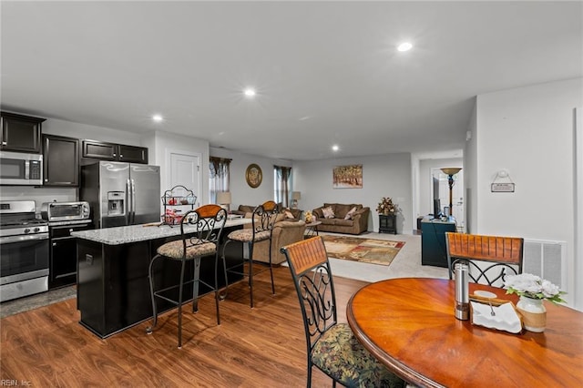 200 Quaint Ridge Rd, Williamsburg, VA 23188 - kitchen with stainless steel appliances, dark cabinetry, a breakfast bar, a center island with sink, and dark wood-type flooring