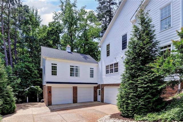117 Shinnecock, Williamsburg, VA 23188 - view of front of home with an attached garage, brick siding, concrete driveway, and a chimney