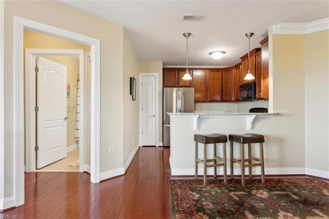 5414 Foundation St, Williamsburg, VA 23188 - kitchen featuring black microwave, a kitchen bar, dark wood-type flooring, a peninsula, and decorative light fixtures