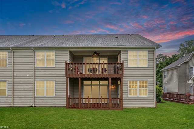 145 Shoal Crk, Williamsburg, VA 23188 - back of house at dusk featuring a balcony, a lawn, ceiling fan, and a shingled roof