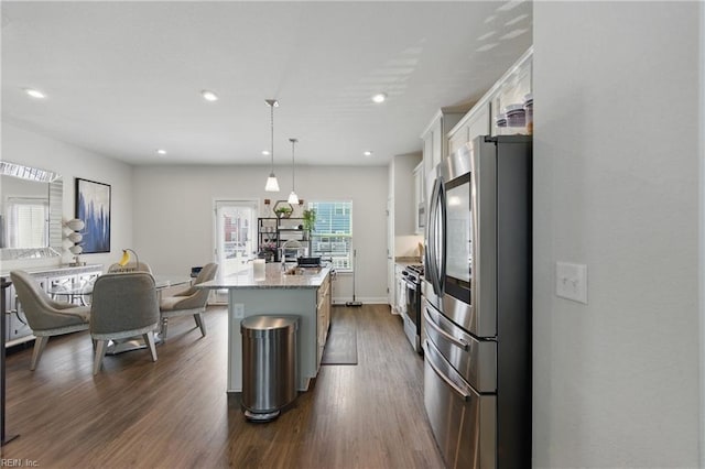 kitchen featuring stainless steel appliances, white cabinetry, a center island with sink, dark wood finished floors, and a sink