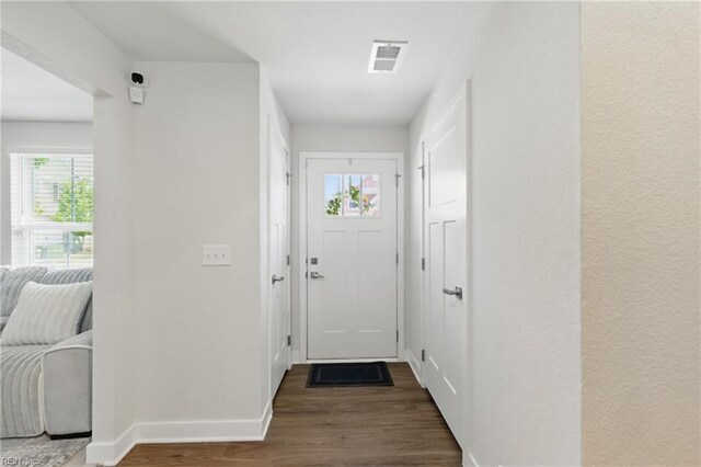 doorway to outside with wood finished floors, healthy amount of natural light, and baseboards