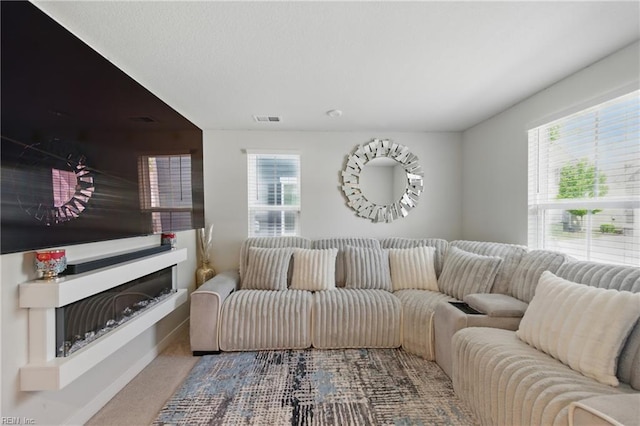 living area with carpet, baseboards, and a fireplace with raised hearth